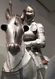 Ritterrüstung auf einer Nachbildung eines Pferdes drapiert, auch das Pferd trägt eine Art Rüstung.